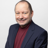 Porträt freundlicher Mann in dunkelrotem Pulli und blauem Blazer